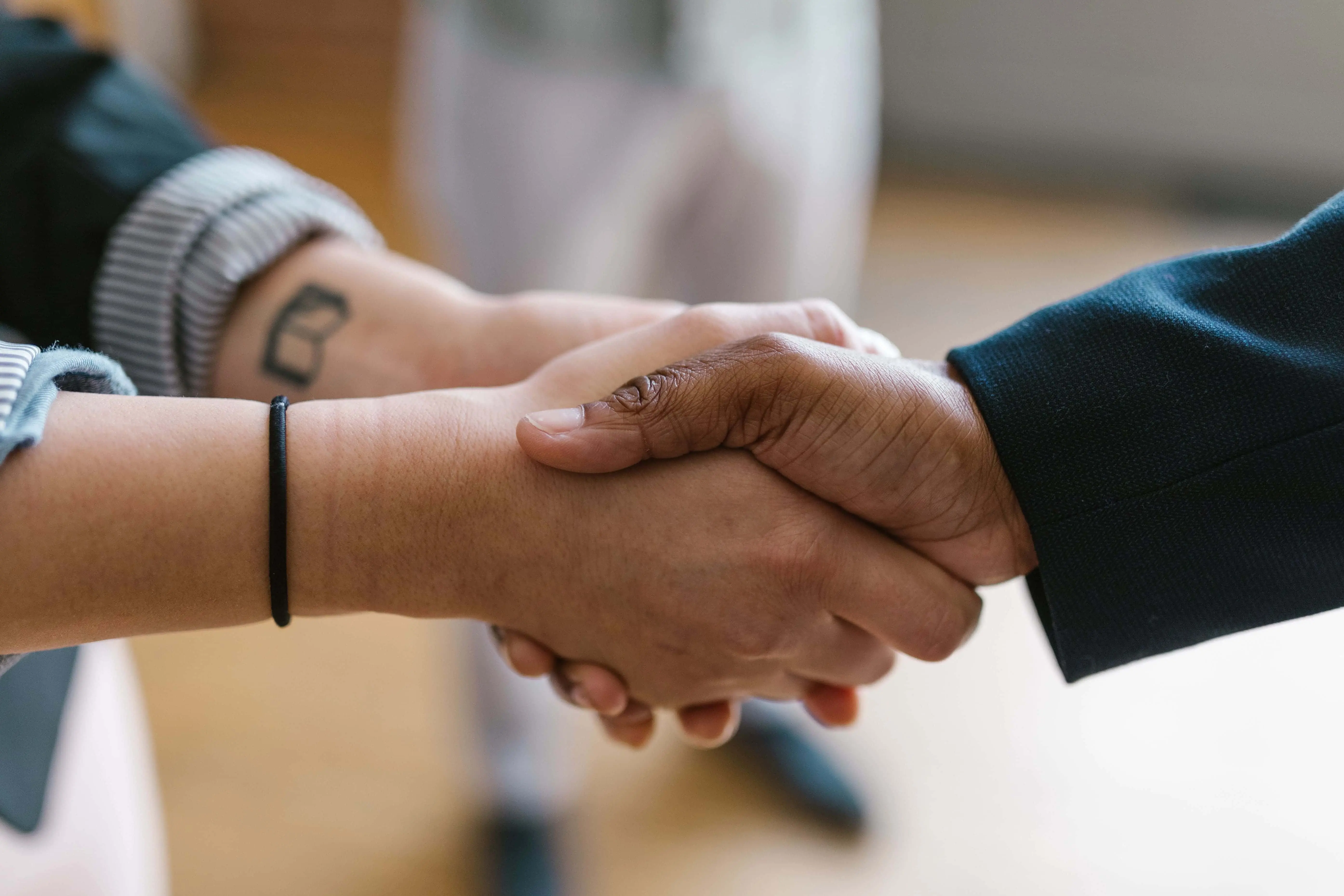 Two people shaking hands across a desk, representing the trust placed in an agent under a power of attorney